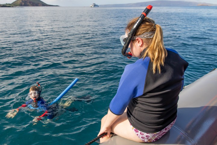 a woman riding on the back of a boat in a body of water