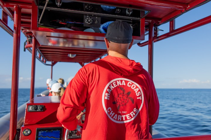 a man standing in front of a boat next to a body of water