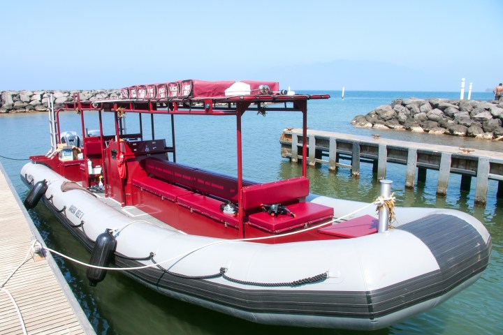 Red and gray inflatable boat docked by the pier on a sunny day.
