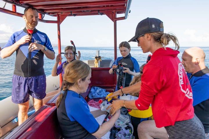 Group on a boat preparing for snorkeling, wearing swim and snorkel gear.