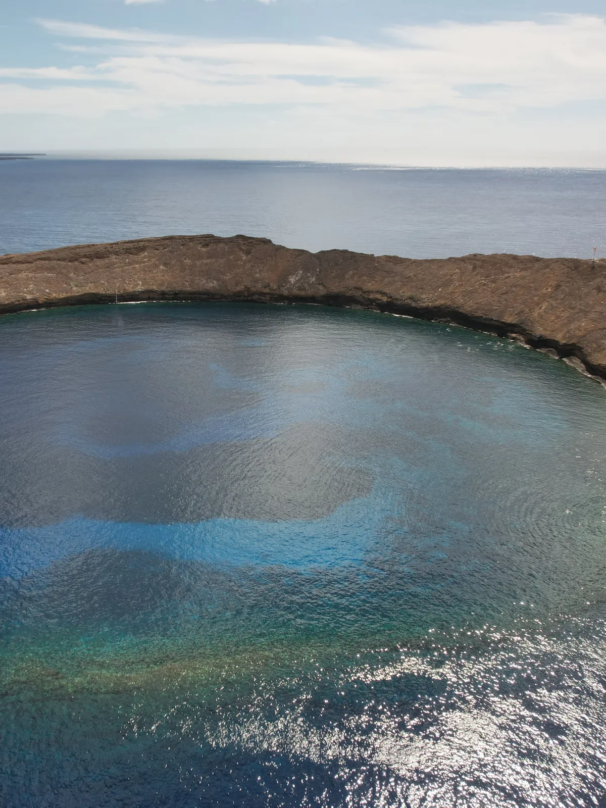 Aerial view of a crescent-shaped island surrounded by blue ocean.